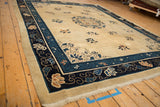 Angled view of the antique Peking carpet's corner, showing the floral motifs in the navy blue border.