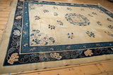 Corner detail of an antique Peking carpet's floral spandrel and navy blue vine border.