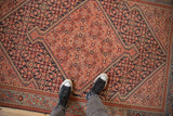 Angled view showing the antique Malayer's rose medallion against the navy Herati-patterned field.