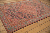 Angled view of an antique Malayer rug with navy Herati spandrels and a rose medallion.