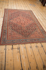 Angled perspective of an antique Malayer rug showing its diamond medallion and traditional Herati pattern.