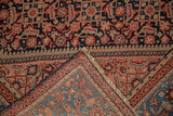 Folded corner of an antique Malayer rug contrasting the detailed Herati pile with the woven back.