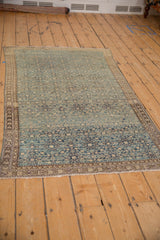 Antique distressed Persian Malayer rug with textured Herati pattern, dusty blue field, and detailed vine border.