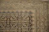 Rich patina on a distressed vintage Malayer rug's corner with faded Herati motifs.