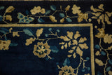Corner detail of the floral blossom border in sand and blue on an antique Peking rug.
