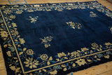 Angled view across the cobalt blue field and floral border of an antique Peking carpet.