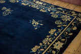 Angled view of an antique Peking carpet's floral border, field spray, and deep cobalt pile.