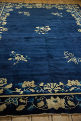 Low angle view of an antique Peking carpet's deep cobalt blue pile and its floral motifs.