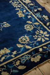 Angled view of the antique Peking carpet's floral border in sand and blue on a rich cobalt field.