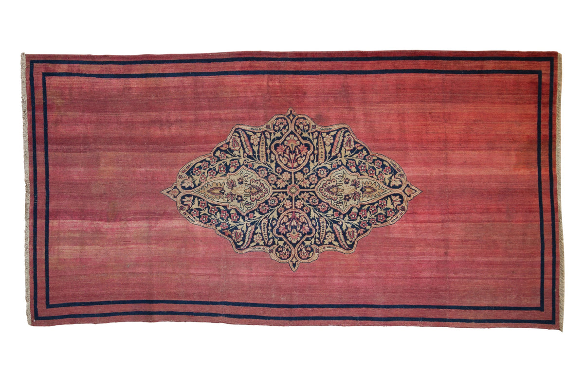 Antique Doroksh rug runner with a navy and beige trefoil medallion with arabesques on a raspberry red field.