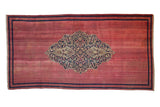 Antique Doroksh rug runner with a navy and beige trefoil medallion with arabesques on a raspberry red field.