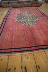 Angled view of an antique Doroksh runner's raspberry field, showing its even wear and navy medallion.