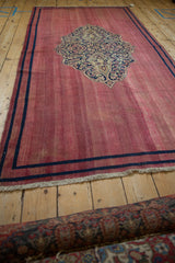 Angled view of an antique Doroksh runner showing its raspberry red field and even wear.