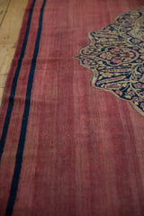 Rewoven navy border and medallion on the worn, raspberry-red field of an antique Doroksh runner.