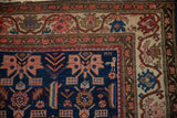 Corner of an antique Malayer rug with a stylized animal motif and classic meandering vine border.