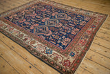Angled view of a 1920s Malayer rug with playful animal motifs on its sapphire blue field.