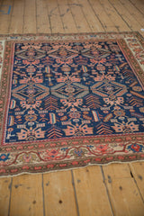 Angled view of an antique Malayer rug's geometric allover field against its traditional vine border.