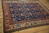 Angled perspective of an antique Malayer rug, detailing its sapphire blue geometric field and ivory vine border.