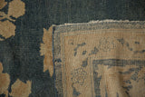 Close-up of distressed antique Kerman rug, showing worn denim blue pile and beige hand-knotted foundation.