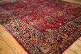 Low angled view of a vintage Sarouk carpet's corner, highlighting its low pile and traditional floral patterns.