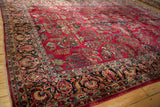 Angled view across the rich texture of a vintage Sarouk's cherry red field and navy border.