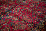Detailed view of the plush cherry-red pile and traditional floral motifs on a vintage Sarouk rug.