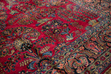 Detailed floral sprays and palmettes in blue and beige on a vintage Sarouk's cherry red field.