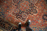Evenly worn pile of an antique Heriz carpet showing its Turtle Samovar border in brick red and blue hues.