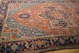 Angled perspective of an antique Heriz carpet's Turtle Samovar border and geometric field.