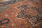 Angled shot showing the geometric vines and serrated leaves on an antique Heriz carpet.