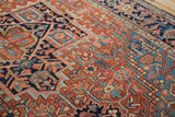 Angled view of an antique Heriz rug's checkered detailing and geometric vines in brick red and navy.