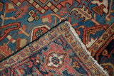 Folded corner of an antique Heriz carpet showing the geometric Turtle Samovar border and fringe.