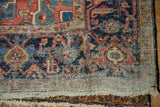 Corner of an antique Heriz carpet showing low pile texture and exposed cotton foundation.