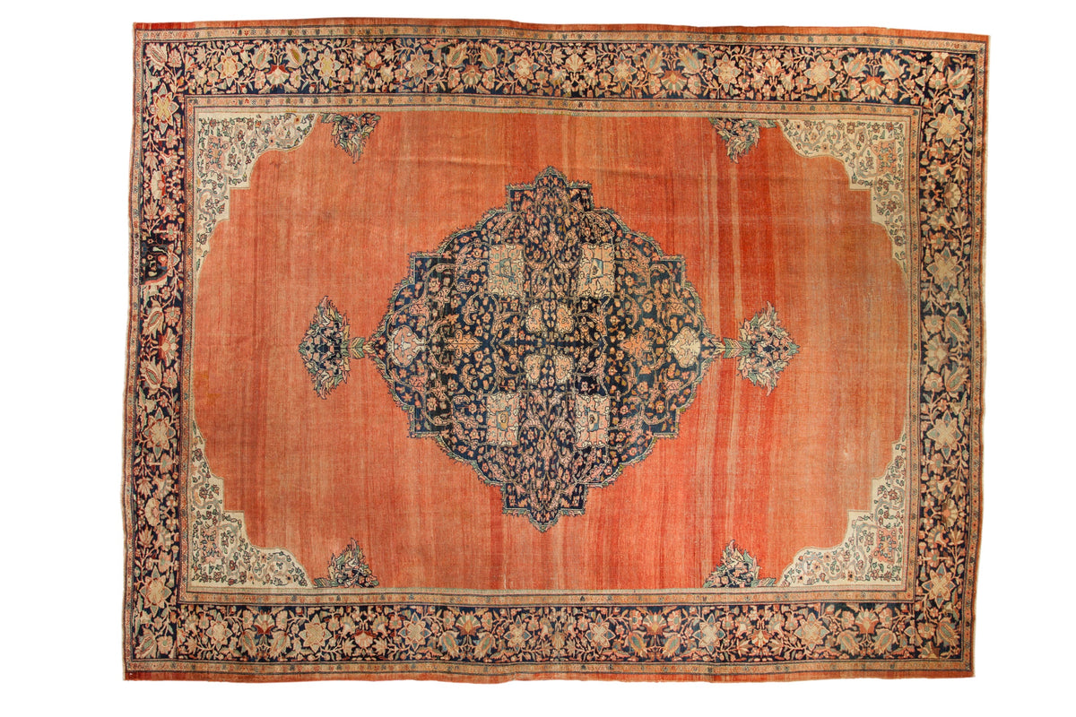 Antique Farahan Sarouk carpet with a navy floral medallion on an abrashed terracotta field with detailed ivory corner spandrels.