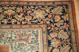 Intricate corner spandrel and wide navy floral border of an antique Farahan Sarouk carpet.