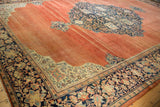 Corner of an antique Farahan Sarouk carpet showing the ivory spandrel and wide navy border against the abrashed terracotta field.