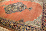 The large navy medallion and ivory spandrel on an antique Farahan Sarouk carpet's abrashed terracotta field.