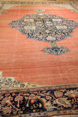 Perspective view of an antique Farahan Sarouk carpet's navy medallion, corner spandrel, and abrashed terracotta field.