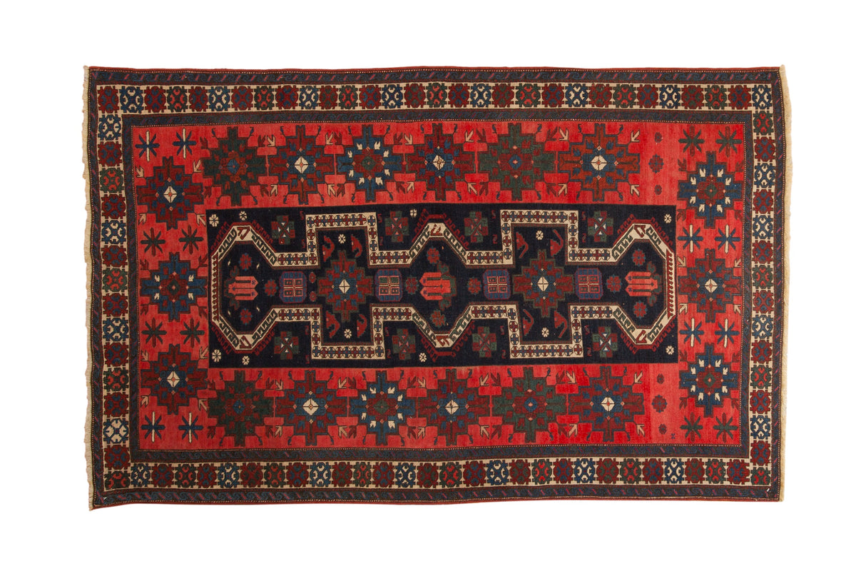 Antique Northwest Persian rug with navy blue stepped medallions on a red field and geometric gul borders.