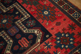 Evenly worn pile of an antique Persian rug showing geometric guls in red, sapphire, and navy blue.