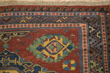 Corner of an antique Caucasian Soumac rug featuring reciprocal wave and geometric pawn motif borders.