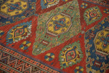 Angled close-up of serrated medallions in jade green and saffron on an antique Soumac rug.