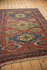 High-angle perspective on an antique Caucasian Soumac rug with bold, colorful geometric medallions.