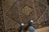 Overhead detail of the antique Farahan Sarouk rug's low pile and intricate navy Herati field pattern.