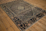 Corner view of an antique Farahan Sarouk rug showing its lotus flower border and dog-eared fold.