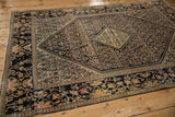 Angled view of a Farahan Sarouk's corner, contrasting the navy floral border with the intricate Herati field.