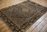 Angled view of an antique Farahan Sarouk rug, showing the central medallion, Herati field, and wide border.