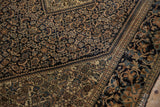 A detailed corner view of the navy Herati field and wide ivory border with oversized lotus flowers.