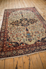 Vased plant motifs and dragon stylization on the finely woven ivory field of a Farahan Sarouk rug.