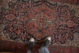 Scalloped roundel medallion with floral bouquets on an antique Farahan Sarouk rug's navy blue field.